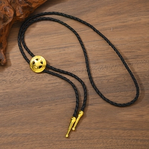 Detail eines Vintage Bolo Ties mit Stern-Anhänger und schwarzer Kordel auf Holzgrund