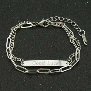 Detail of silver Cuban chain bracelet with engraved Good Luck rectangular plate