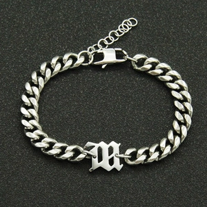 Macro view of silver Old English letter M charm on adjustable Cuban chain bracelet