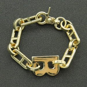 Detail of gold chunky H-link chain bracelet featuring a bold letter B charm and lobster clasp