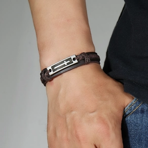 Vintage men's braided leather bracelet featuring a metal cross charm on the wrist