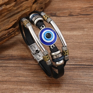 Detail of multi-layer braided leather bracelet with blue Evil Eye bead and steel clasp