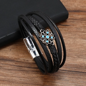 Dettaglio bracciale multistrato in pelle nera con fiore blu e chiusura magnetica