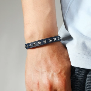 Men's dark blue leather bracelet featuring silver square studs on a male wrist