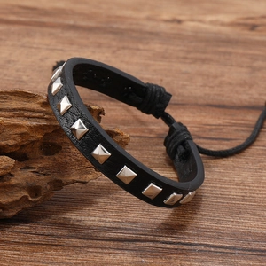 Detail of black leather punk bracelet with square silver studs on vintage wood backdrop