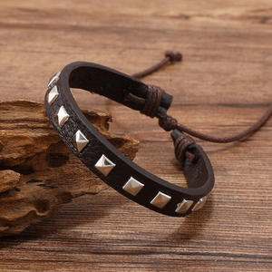 Detail of adjustable dark brown leather bracelet with silver pyramid studs on wood