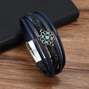 Dettaglio del bracciale multistrato in pelle con ciondolo a margherita blu e chiusura magnetica