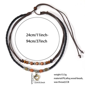 Detail showing vintage heart pendant and textured wooden beads on a layered woven necklace