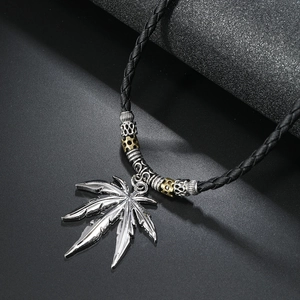 Macro detail of alloy cannabis leaf pendant with vintage beads on black woven cord