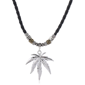 Detail of silver leaf pendant on black woven leather cord with vintage metal beads
