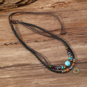 Vintage turquoise beaded necklace with ancient coin pendant on rustic wooden background