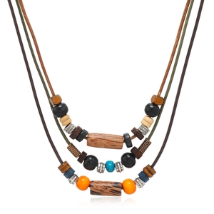 Détail d'un collier bohème à trois rangs avec des perles en bois colorées et charms arbre de vie