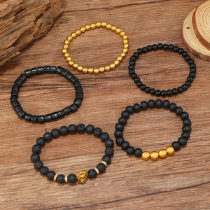 Set 5 bracciali in pietra lavica con testa di leone dorata su fondo in legno scuro