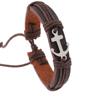 Detail of a brown braided leather punk bracelet with a silver anchor charm on white background