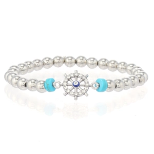 Détail du bracelet en perles argentées avec charme gouvernail micro-pavé et motif œil maléfique