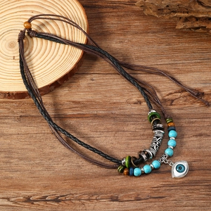 Bohemian multi-layer necklace with turquoise beads and evil eye pendant on wood background