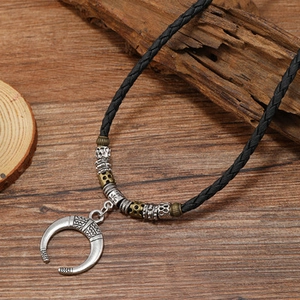 Macro detail of crescent pendant with tribal patterns on bohemian brown wood background