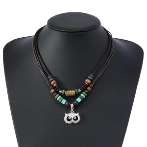 Détail d'un collier bohème double couche avec perles et pendentif hibou argenté vintage