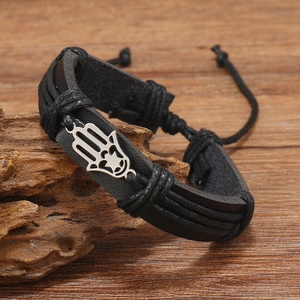Macro detail of multi-layer black leather woven bracelet with silver Hamsa Hand charm