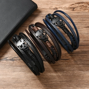 Detailed close-up of punk braided leather bracelets with skull charms on a wooden surface