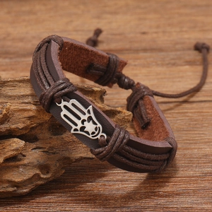 Close-up of vintage multi-layer braided leather bracelet with Hamsa Hand on wood