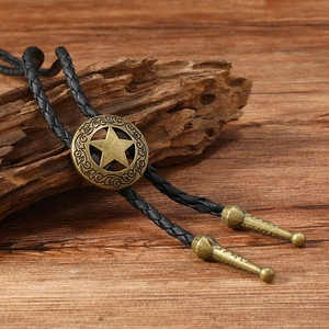 Retro bronze western bolo tie with star medallion and black woven cord on wood