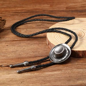Detail of vintage silver cowboy hat bolo tie with black braided leather cord on wood