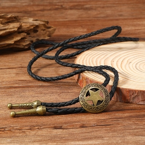 Close-up of vintage bronze star bolo tie with black braided leather and ornate metal tips