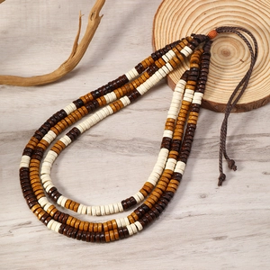 Detail shot of triple-layer wooden bead necklace with woven cord on natural wood background