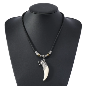 Detail of gothic wolf head pendant with white tusk on black braided leather necklace