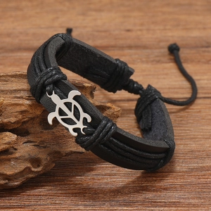 Detailed close-up of a multi-layer black leather bracelet with a silver turtle charm