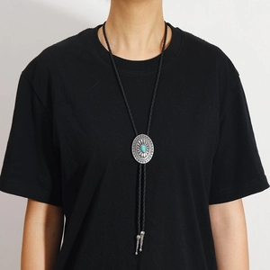 Détail de cravate bolo western avec pendentif turquoise et corde en cuir tressé noir