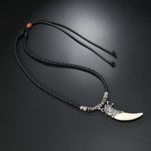 Detailed close-up of a vintage wolf head pendant on a black braided cord necklace