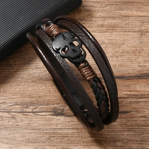 Close-up of men's multilayer leather bracelet featuring a matte black skull charm detail