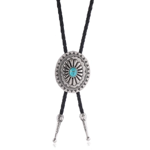 Détail d'une cravate bolo vintage avec pierre turquoise et pendentif en métal gravé