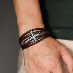 Detail of multi-layer leather bracelet with metal cross and magnetic clasp on male wrist