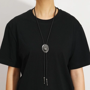 Detail of vintage cowboy hat bolo tie with antique silver finish on black woven cord