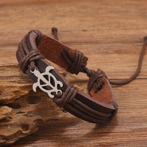 Detailed view of woven leather bracelet with vintage silver turtle charm on wood