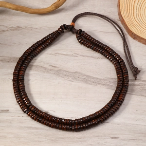 Detail of double-layer bohemian brown wooden bead necklace on a natural wood surface