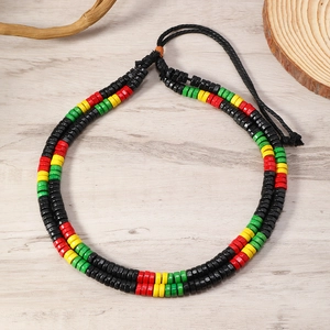 Detail of Rasta colored beads with black woven rope on a natural wooden background