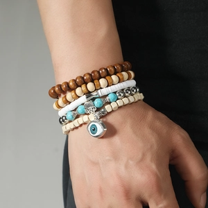 Detail of bohemian layered beaded bracelets featuring wood, turquoise, and Evil Eye charm