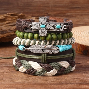 Bracelet multicouche bohème en cuir avec croix turquoise et plumes sur fond de bois
