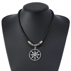 Detail of a vintage compass pendant necklace on black braided cord with silver beads