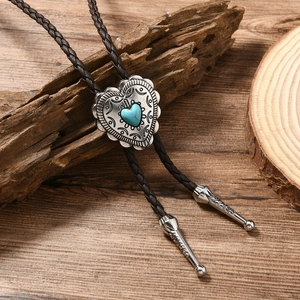 Detail of heart-shaped turquoise pendant and braided leather cord on rustic wood