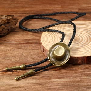 Detail of vintage copper cowboy hat pendant on black braided bolo tie with engraved metal tips