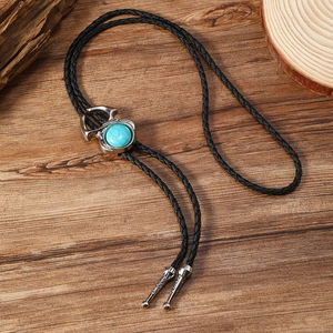 Détail de la cravate bolo vintage avec pierre turquoise sur fond de bois rétro
