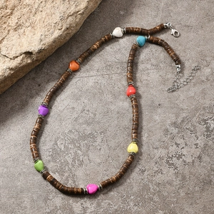 Détail d'un collier bohème avec perles en bois, cœurs colorés et fermoir mousqueton