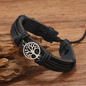 Detail of handmade braided leather bracelet with silver tree of life charm on wood