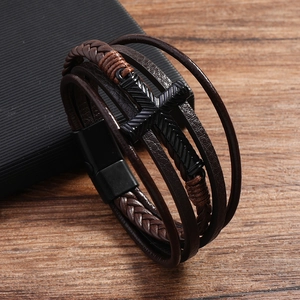 Detail of multilayer brown leather bracelet with cross charm and black magnetic clasp