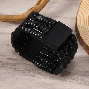 Detail of multi-layer black wooden bead bracelet on a rustic wood slice background